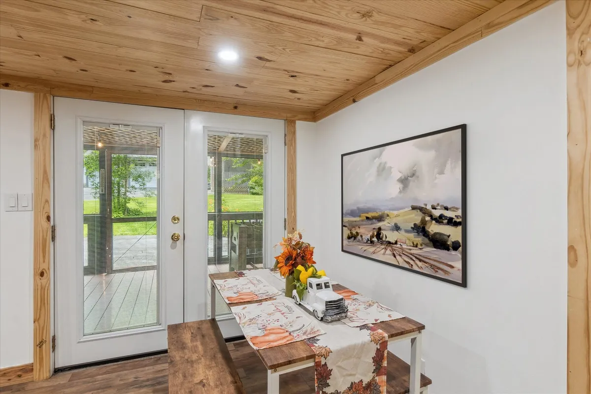 This image highlights a large dining table beautifully set with a floral centerpiece, situated near expansive glass doors that open to the outdoors. Framed artwork on the wall adds a touch of homey sophistication, while the setting promises comfortable, communal dining.