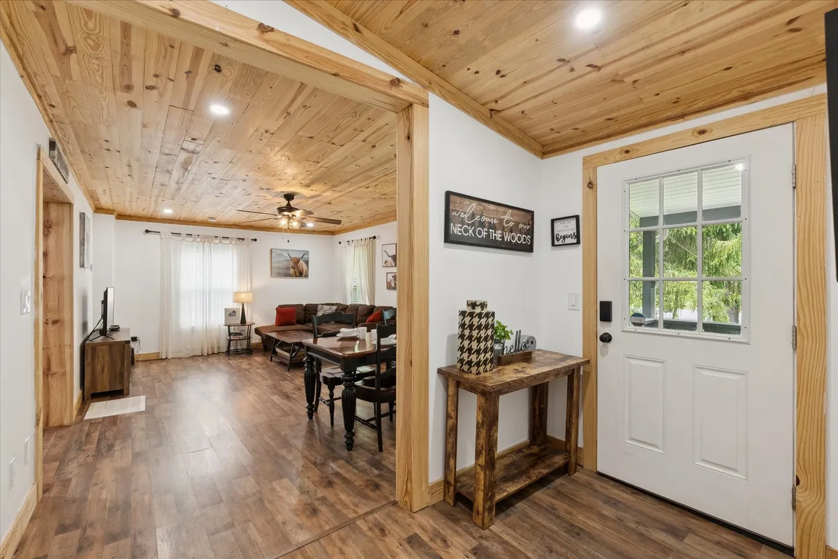 This image captures a welcoming living room with a wooden table, comfortable seating, and art on the wall. The arrangement suggests a zone for gathering, relaxing, and enjoying shared activities such as watching TV or hosting friends.