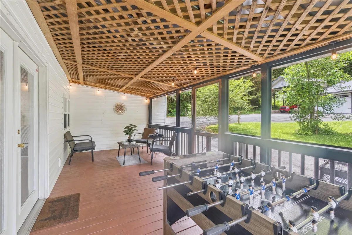 This exterior scene features a foosball table placed in a cozy outdoor seating area, complemented by decorative wall art and string lighting overhead. The space is set up for playful social interactions, with comfortable seating encouraging guests to relax and join in the fun.